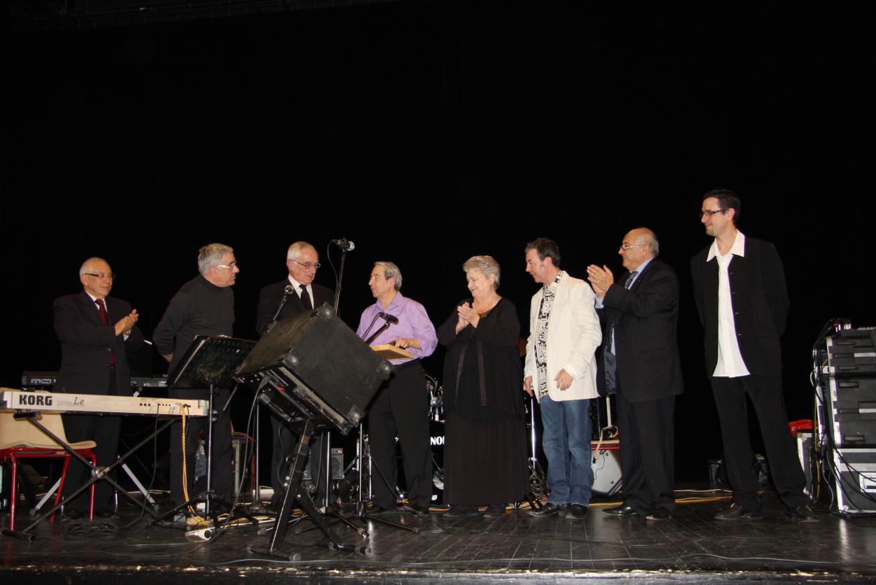 Remise d'un double disque d'or à André ROQUES pour &#34;Adio Pulchinella&#34;. De gauche à droite: Mr Mellinger (conseiller général du Lot) - Bernard Mazelié ( président de l’Adas ; organisateur de la soirée) - Mr Martin Malvy (président du conseil régional de Midi-Pyrénées) - André Roques - Mme Paulo (maire de Figeac) - Thierry Roques (chef d’orchestre d’Enrico Macias) - Mr Albert Henry Ankri (direction de K’Danse productions) - Christophe Martel présentateur de la soirée, Totem fm de Rodez).